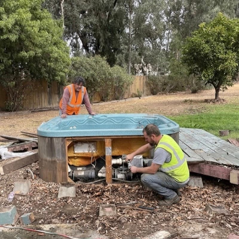 Junk Tigers crew cutting apart a hot tub for spa removal in a backyard
